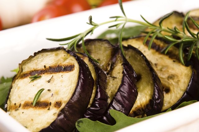 Grilled eggplant slices on a plate with fresh rosemary