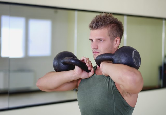 Handsome young man working out in gym with kettlebells