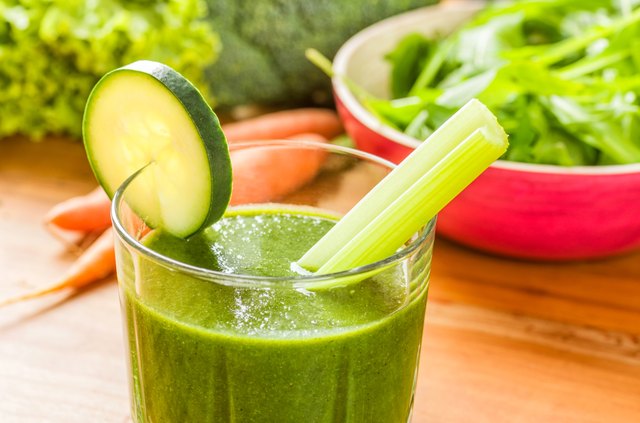 Green smoothie with fresh vegetables on a wooden background