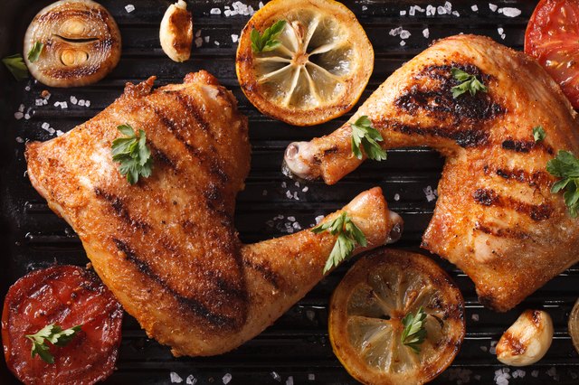 chicken legs and vegetables on grill macro. Top view horizontal