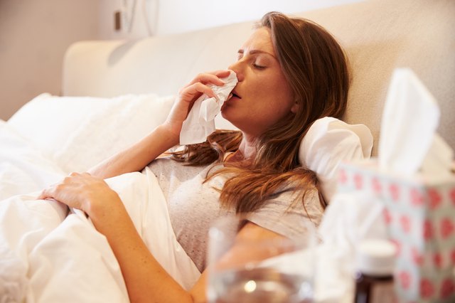 Woman Suffering From Cold Lying In Bed With Tissue