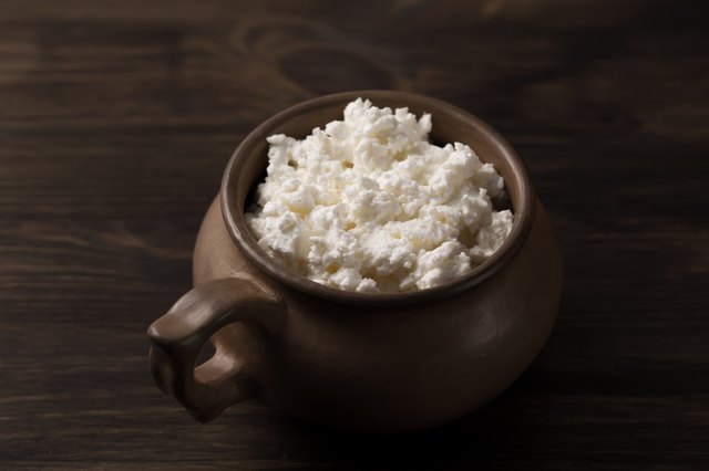 fresh tasty curd in pot on wooden background.