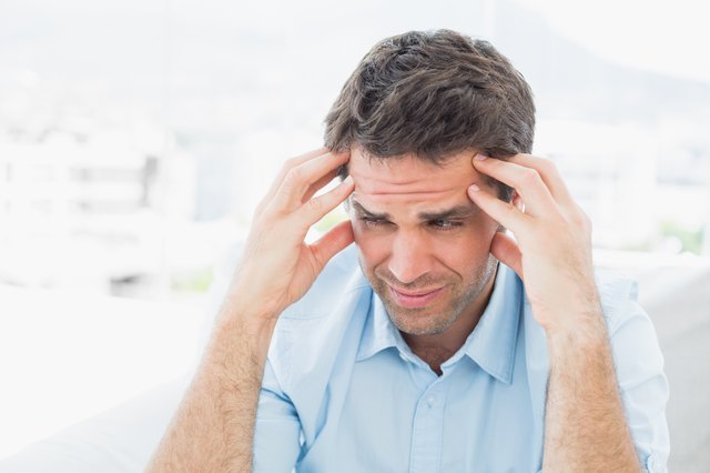 Frowning man sitting on the couch with a headache