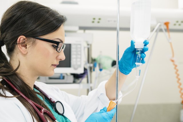 Young woman doctor anesthesiologist dressed in green gown, puts