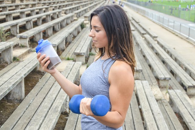 Woman drinking a protein shake and lifting weights