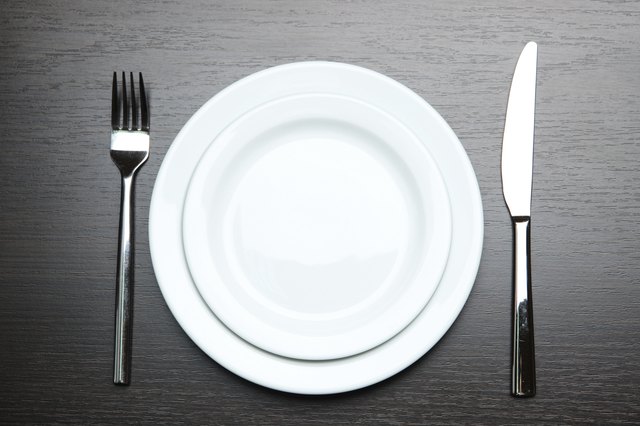 Knife, plate and fork, on wooden background