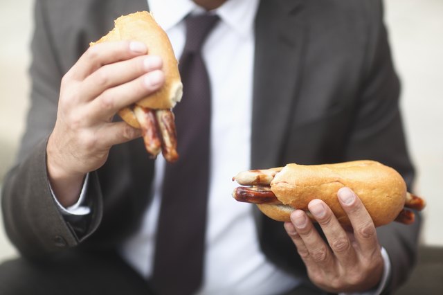 Businessman holding two hotdogs outside