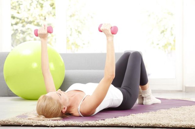 Portrait of middle age woman working out with dumbbells at home.