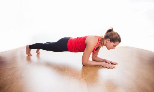 Young woman exercising - doing a plank in a studio