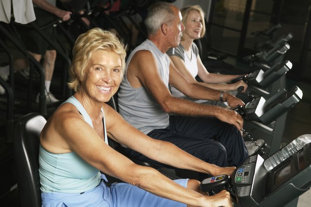Mature woman on cycling machine in gym, smiling, portrait
