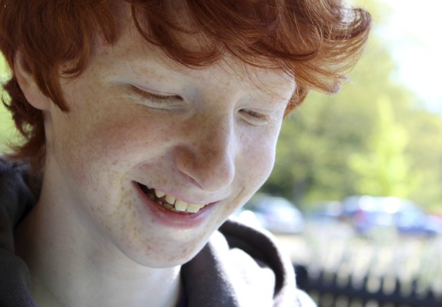 Image of happy boy with red hair smiling to himself