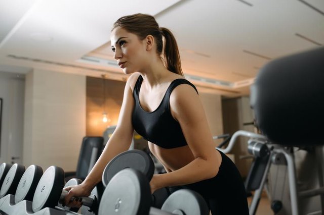 Beautiful woman take a dumbbell in gym