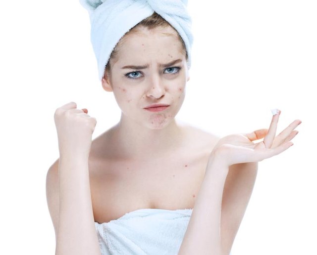 Scowling girl in shock of her acne with a towel on her head. Woman skin care concept / photos of european girl on white background