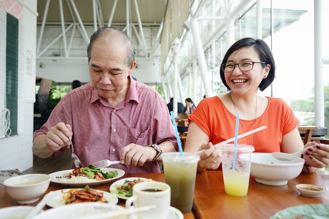 Asian lady and mature man having a meal together