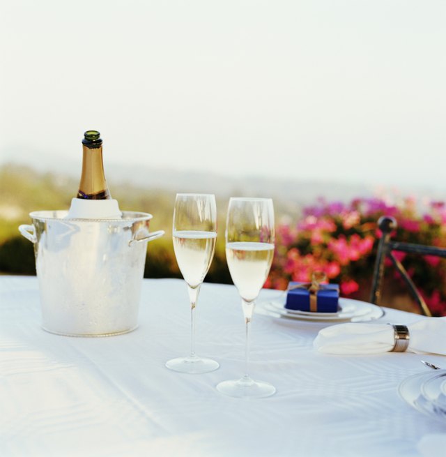 Two glasses of champagne on table, bottle in ice bucket in background