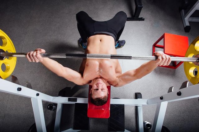 young bodybuilder training in the gym: chest - barbell incline bench press - wide grip, top view