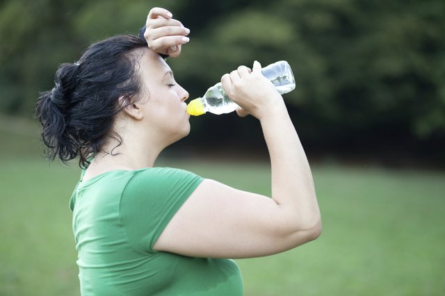 Sweaty overweight woman drinking water after a long run