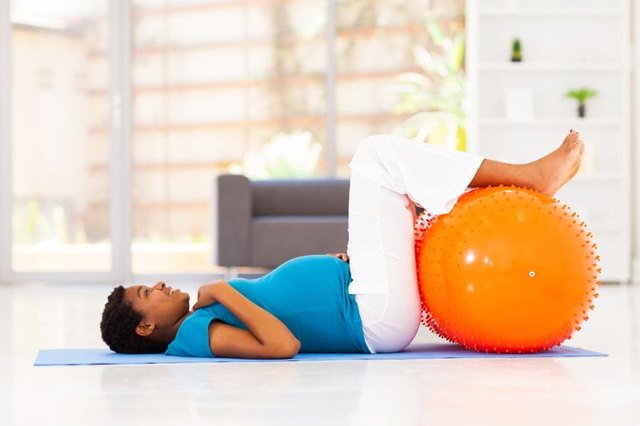 happy pregnant african woman workout on exercise mat at home