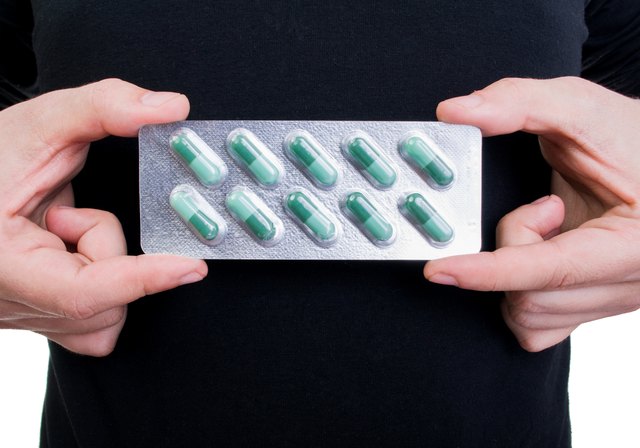 Hands holding blister with green pills