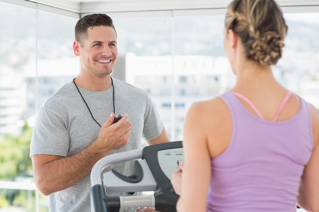 Trainer helping woman on treadmill