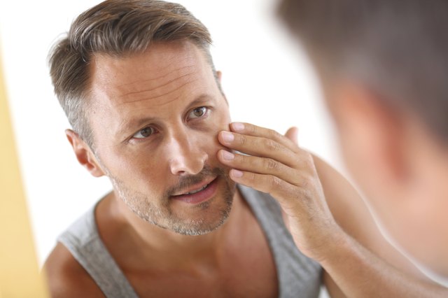 Man in bathroom looking at mirror