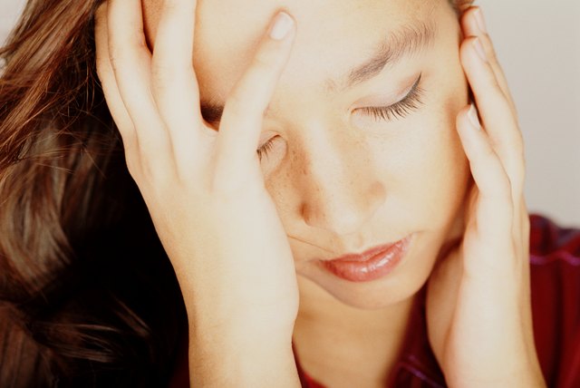 Young woman with eyes closed, head in hands, close-up