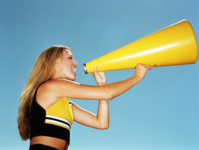 Cheerleader yelling through megaphone, low angle, side view