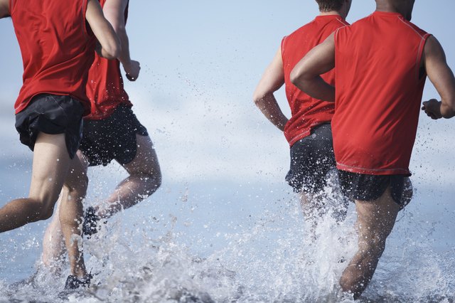 Men running in ocean, low section