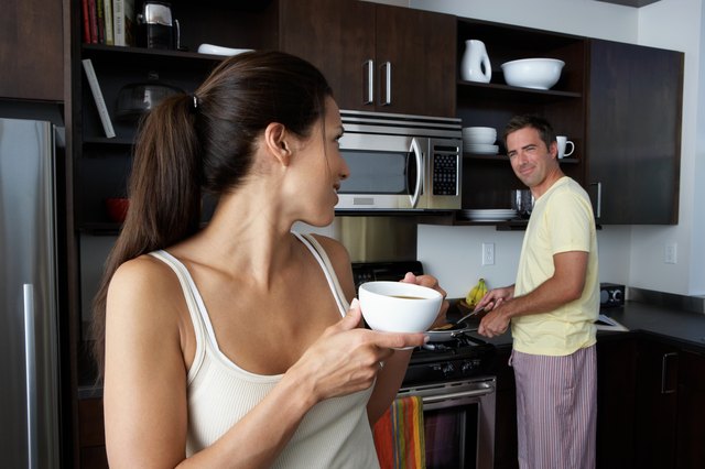 Man and woman preparing breakfast and smiling at one another