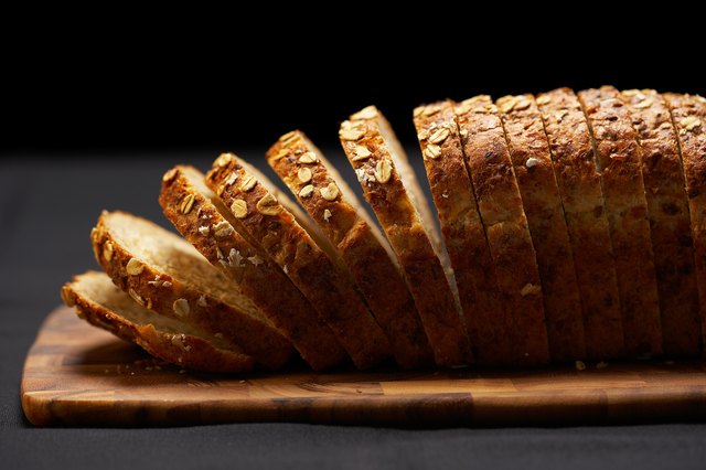 Sliced loaf of whole grain bread on cutting board