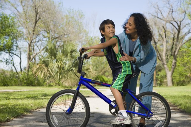 Hispanic mother smiling at son on bicycle