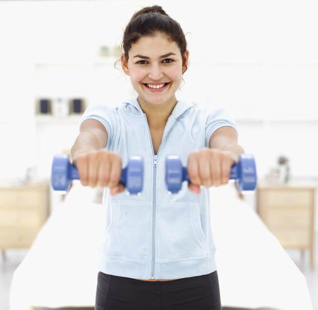 Portrait of a young woman smiling exercising with dumbbells