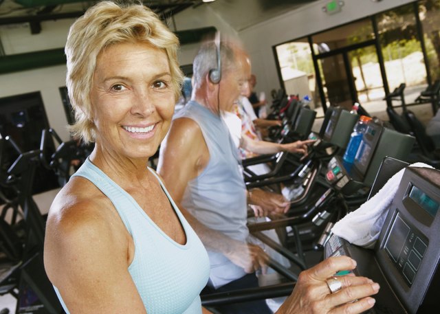 Senior woman using machine in gym, smiling, portrait, close-up
