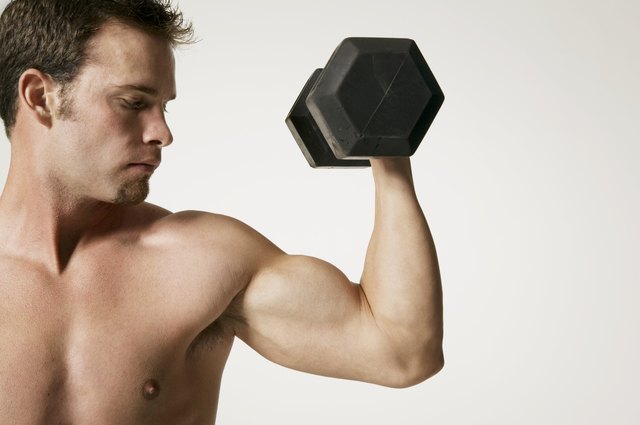 Muscular man lifting weight in studio