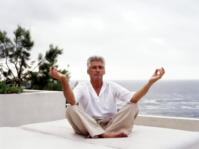 Mature man meditating by ocean, eyes closed