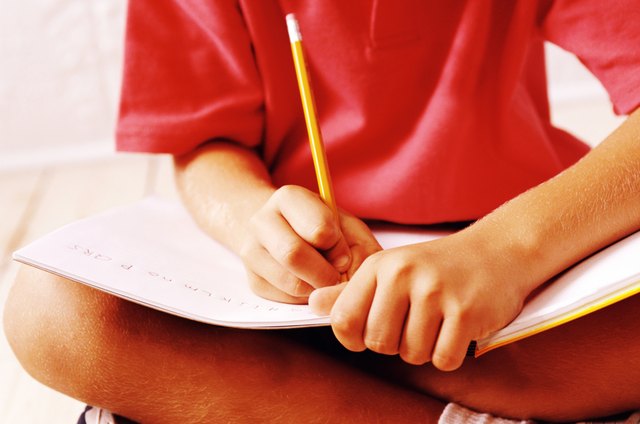 close up of a child's (8-10) hands writing in a notebook