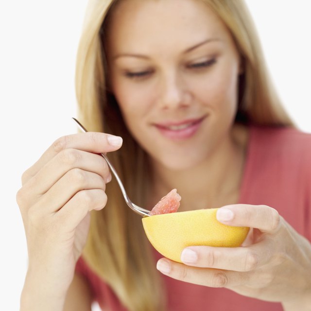 Young woman eating grape fruit with a spoon