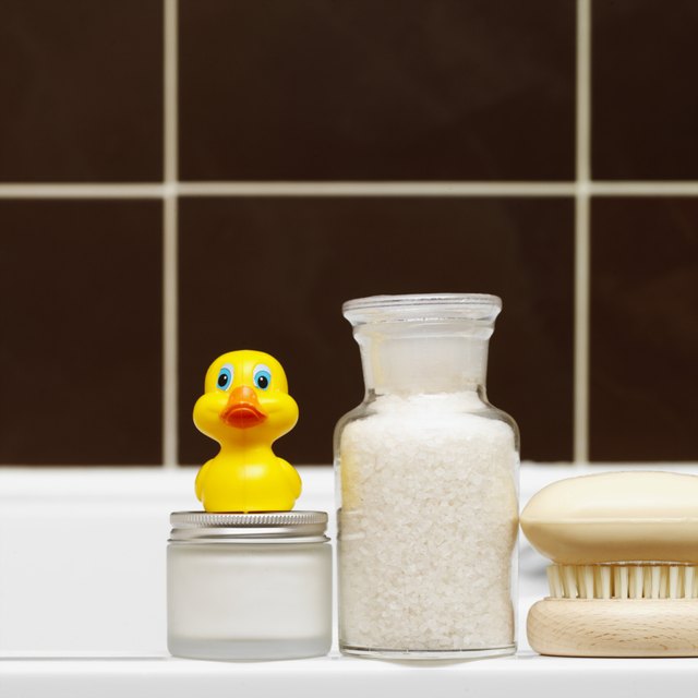 Close-up of toiletries and rubber duck on side of bath