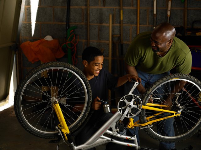 Father and teenager oiling bicycle chain