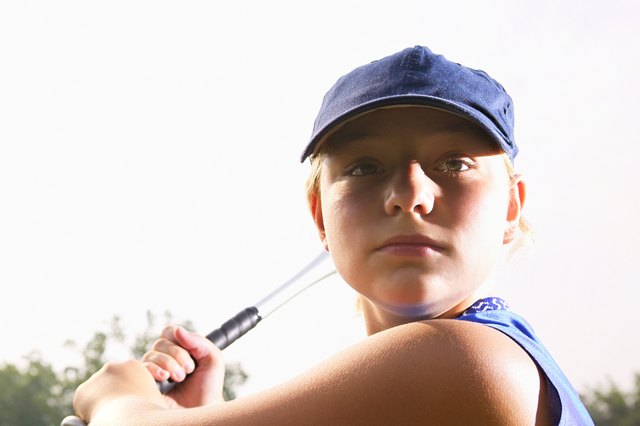 A softball player looking over her shoulder preparing to hit the ball