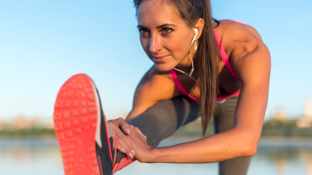 Fitness model athlete girl warm up stretching her hamstrings, leg