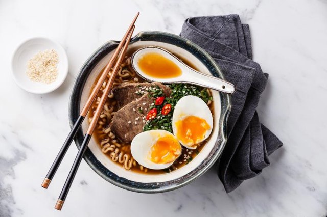 Miso ramen Asian noodles with beef and egg in bowl on white marble background.