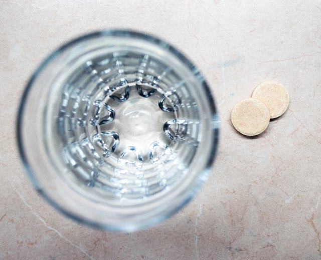 Effervescent/Fizzing Tablets/Pills Next to a Glass of Water Overhead View