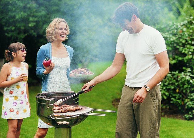 Family Cooking a Barbecue in Their Garden