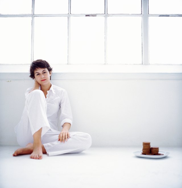 portrait of a woman sitting on the floor beside a plate of cookies