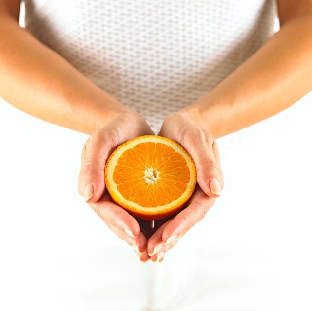 Hands holding half of orange