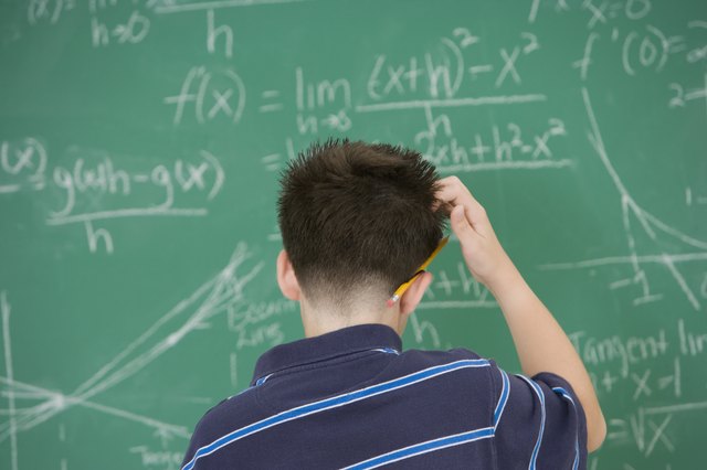 Hispanic boy scratching head in front of blackboard