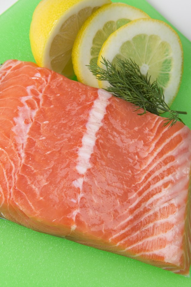 Salmon fillet on plastic cutting board with garnishes