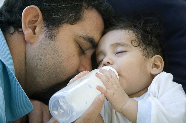 Close-up of a mature man feeding his baby with a bottle