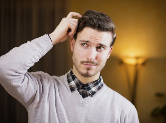 Confused or doubtful young man scratching his head